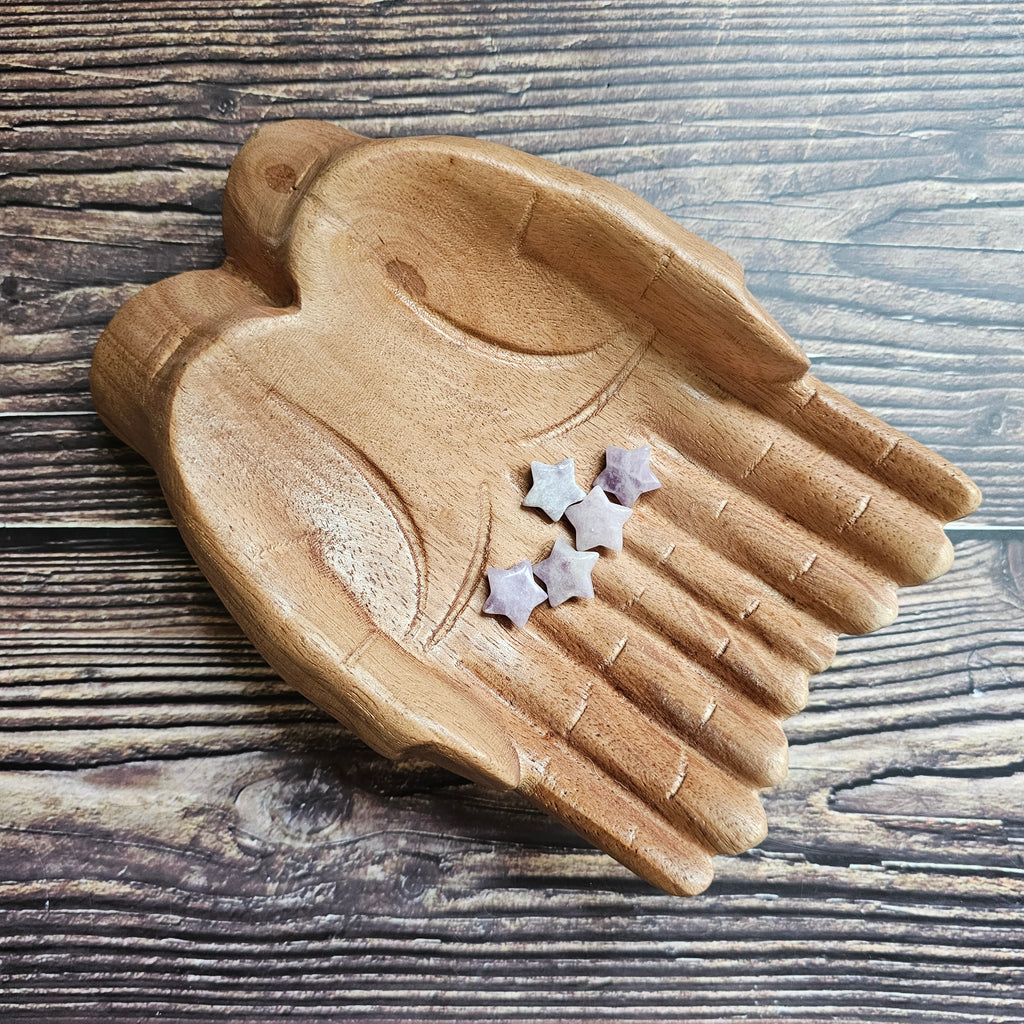 A collection of mini star-shaped Lepidolite stones, placed on a wooden surface.
