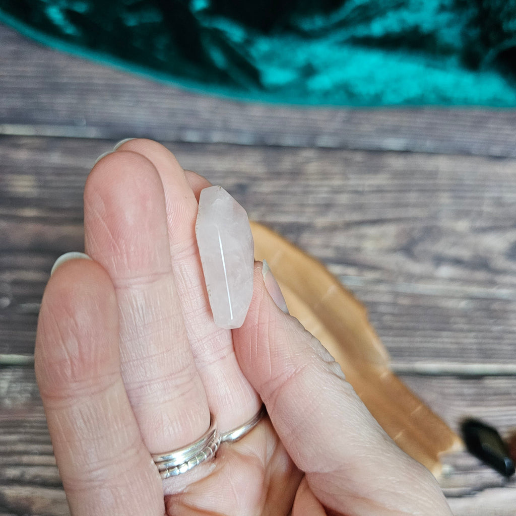 A Rose Quartz crystal coffin is being held in someone's hand