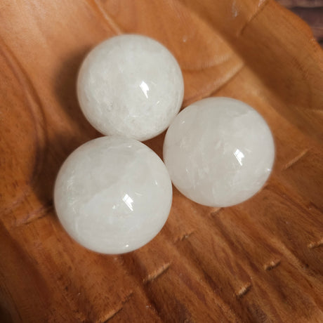 Three clear quartz spheres placed on a wooden surface.