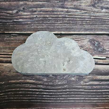 A carved Pink Amethyst crystal shaped as a cloud laid on a wooden background