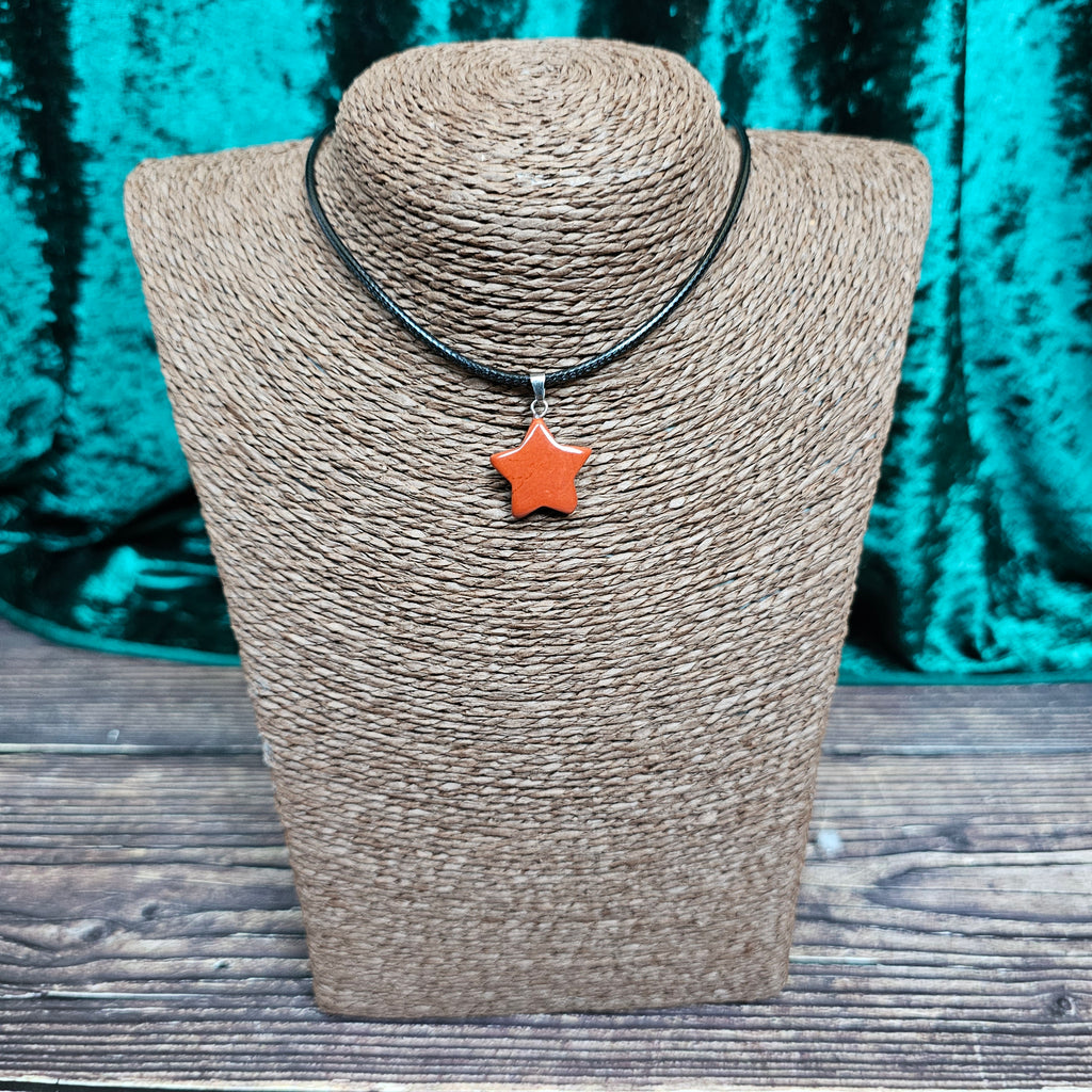 A star-shaped crystal pendant displayed on a brown mannequin, with a black cord.