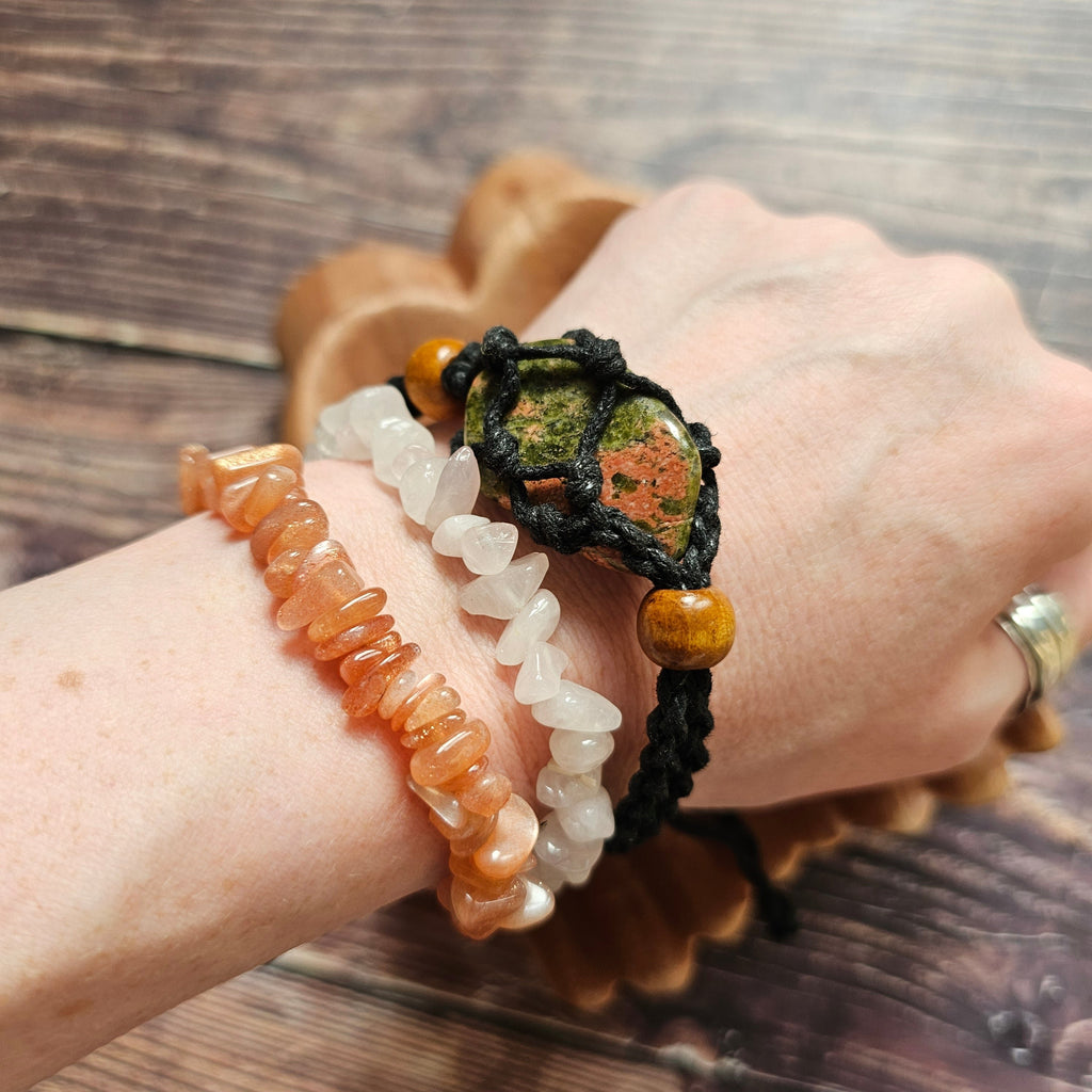 A black-coloured crystal cord bracelet worn on a wrist alongside other crystal bracelets