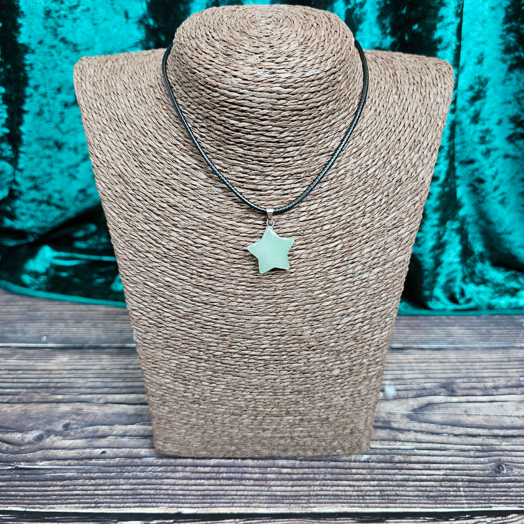 A star-shaped crystal pendant displayed on a brown mannequin, with a black cord.