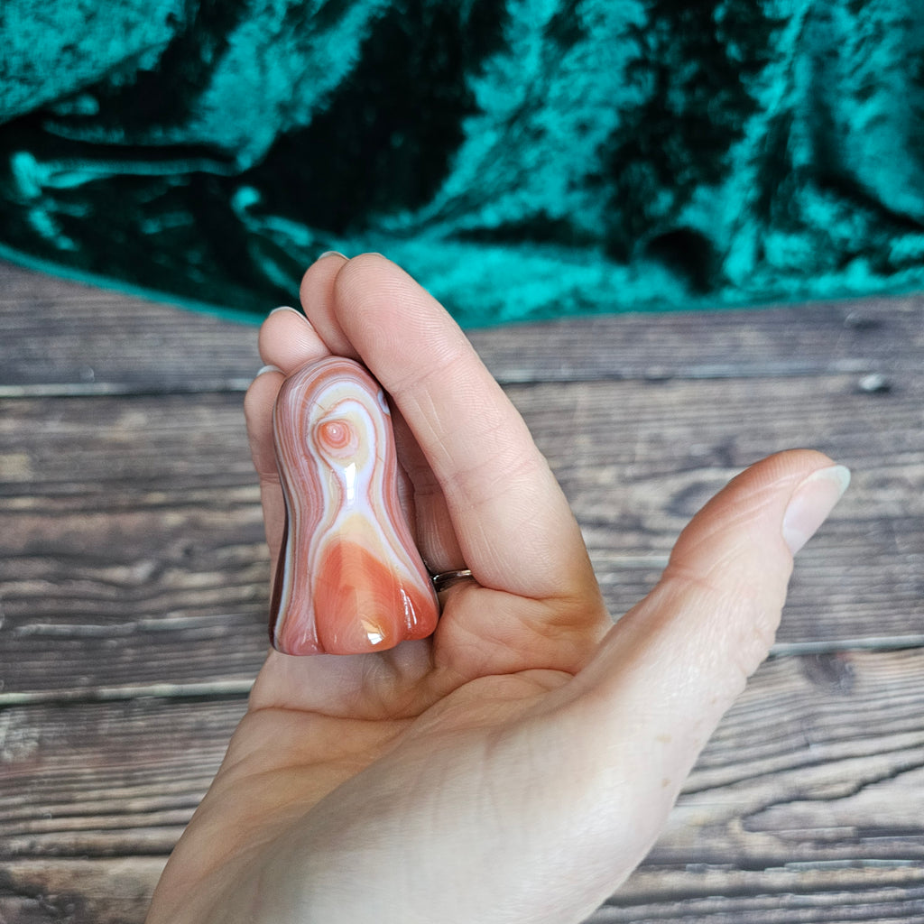 The side of a Carnelian carved crystal ghost held in a person's hand