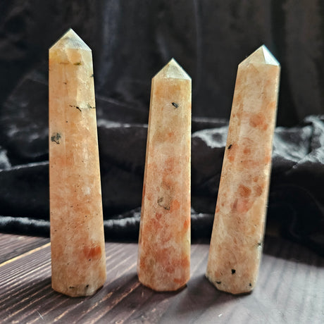 Three sunstone obelisks stood on a wooden surface 