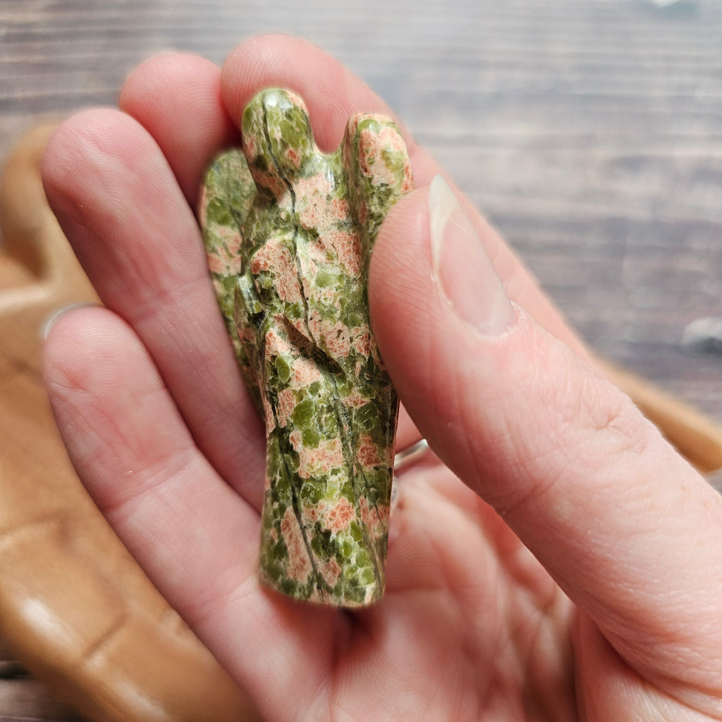 A carved crystal angel figurine held in a hand