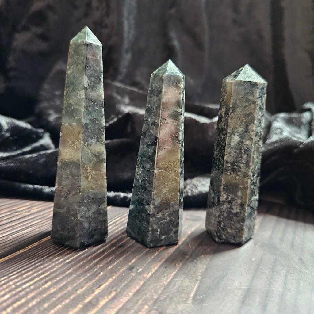 Three Larvikite obelisks stood on a wooden surface 