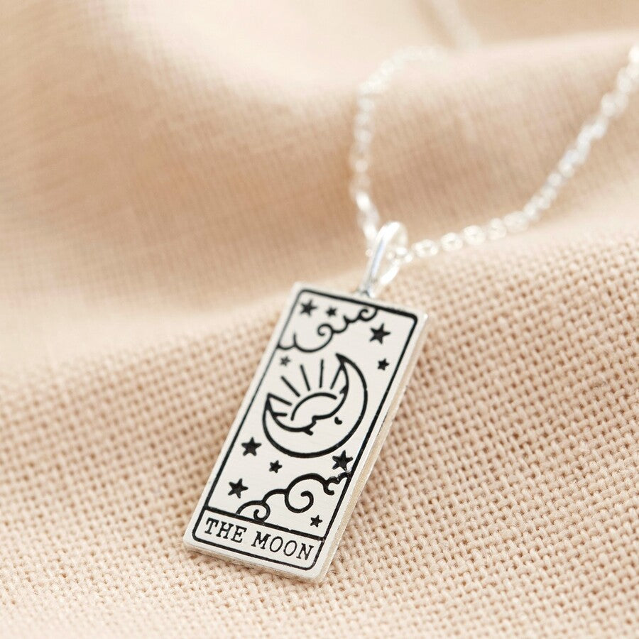 A close up of a silver tarot necklace with a pendant featuring a rectangular design, the 'Moon' card from tarot.