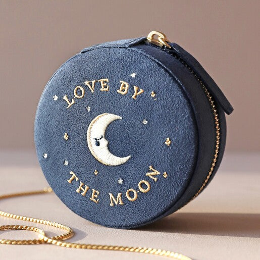 A closed navy blue travel jewellery case with gold embroidery, featuring an embroidered "love by the moon" design and a zippered top