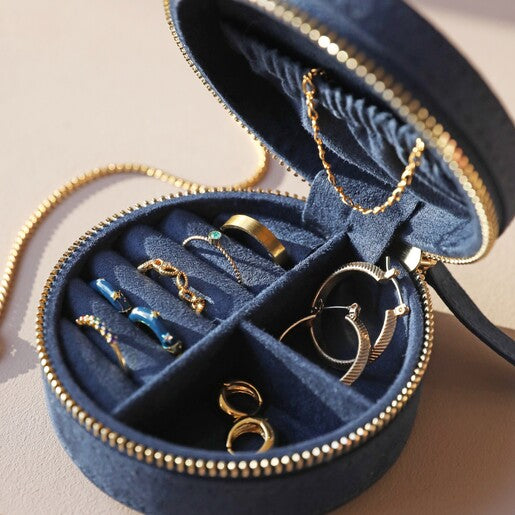 A navy blue travel jewellery case with gold embroidery, featuring a textured surface, a zippered top, and jewellery rolls visible inside.